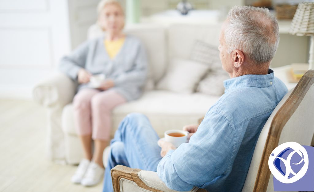 An older couple are drinking tea in their living room. The man is in a chair in the foreground while the woman is out of focus on a couch. The image illustrates salary sacrifice pension issues.